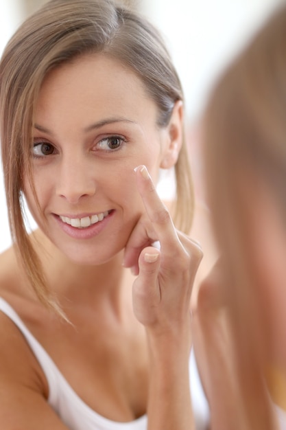 Young woman applying  anti-wrinkles cream