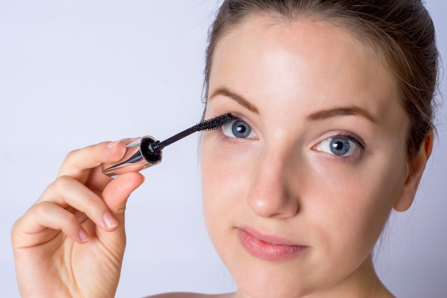 Young woman applying black mascara.