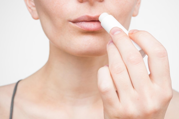 young woman applying moisturizing lip balm. lip care concept