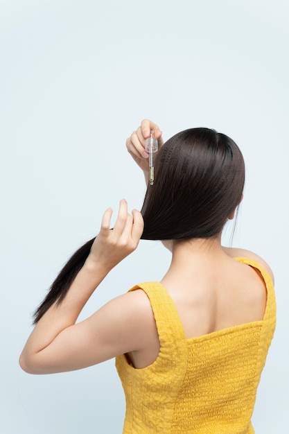 Young woman applying natural organic essential oil on hair