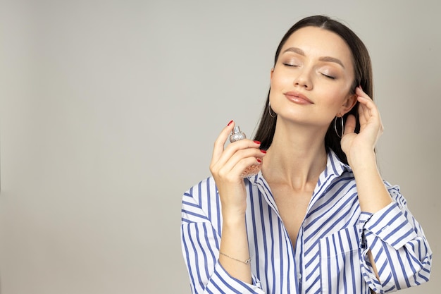 Young woman applying perfume on white background space for text