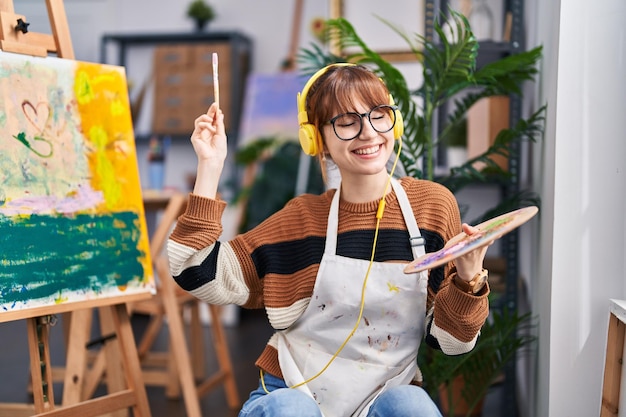 Young woman artist listening to music drawing at art studio