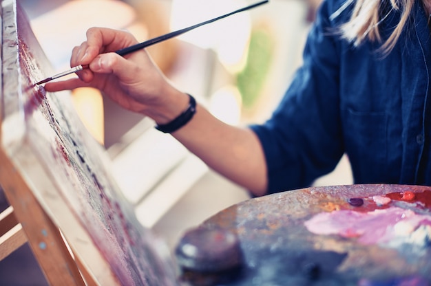 Young Woman Artist Working On Painting In Studio.