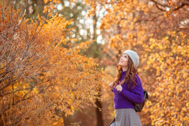 A young woman in an autumn park in a purple sweater