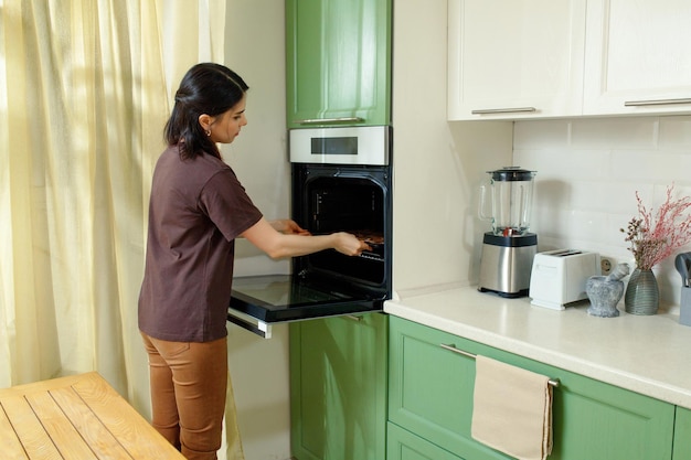 A young woman bakes in an oven that is ergonomically built in at chest level