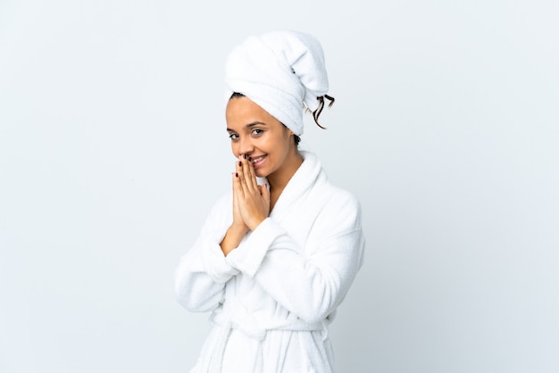 Young woman in bathrobe over isolated white wall keeps palm together. Person asks for something