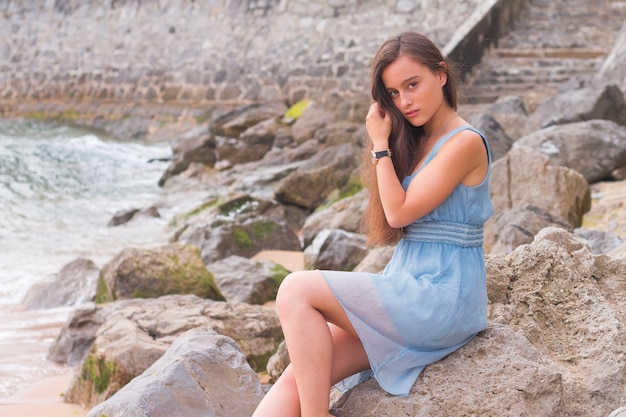 Young woman at the beach with a turquoise dress.