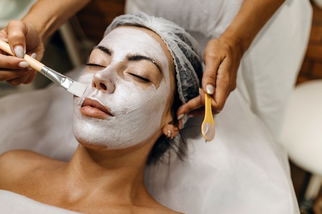 Young woman at a beauty salon with a face cream mask