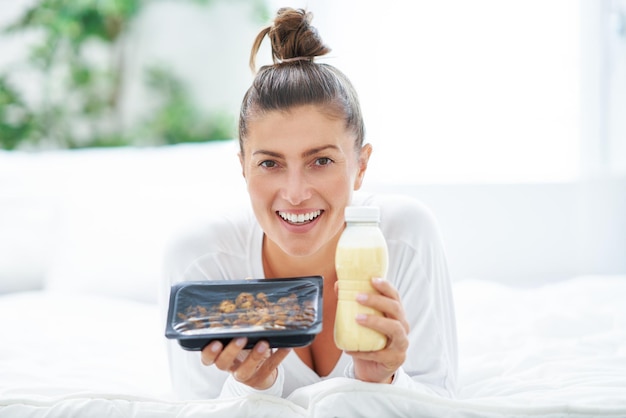 Young woman on bed with food catering box