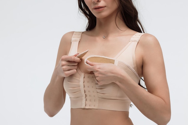 Young woman in beige bra on white background