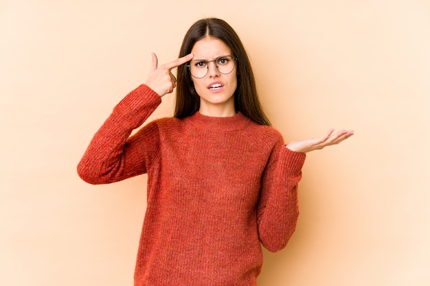 Young woman on beige showing a disappointment gesture with forefinger.