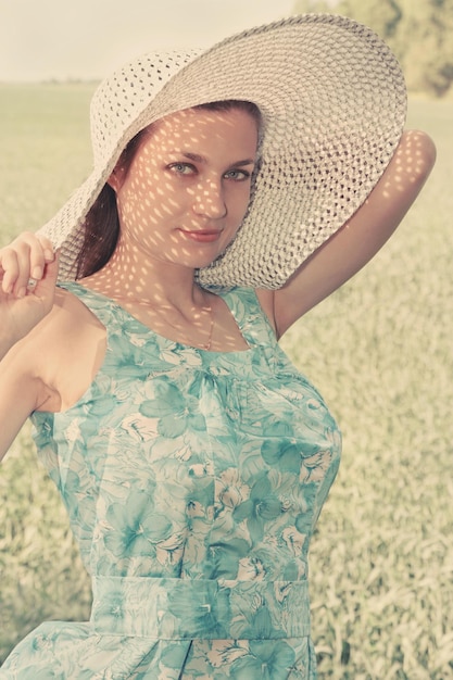 Young woman in a big hat on the field