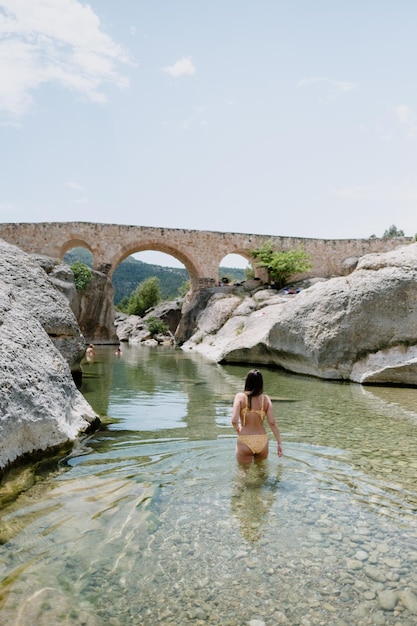 Young woman on bikini taking a swim in a transparent water river in Spain