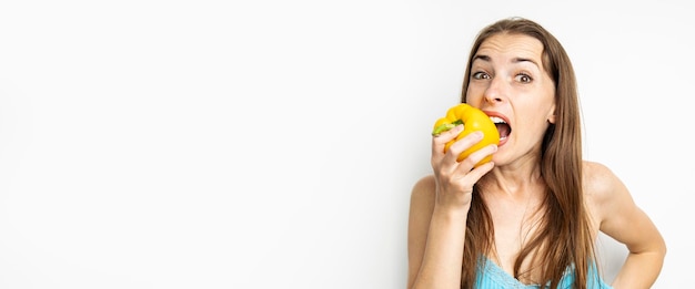 Young woman biting whole fresh yellow paprika on white background Banner