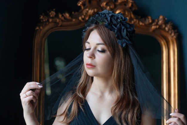 A young woman in a black dress and with a black veil on her head