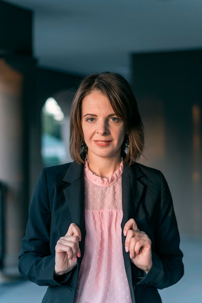 Young woman in black jacket and pink blouse on the street Business woman in formal attire outdoors