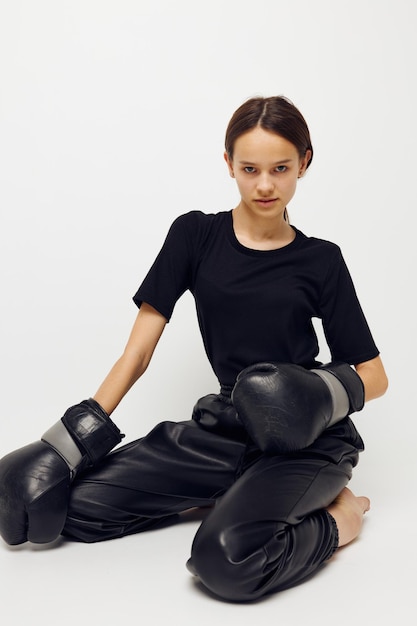 Young woman in black pants on the floor boxing gloves isolated background