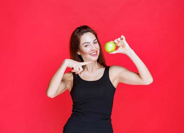 Young woman in black singlet holding green apples