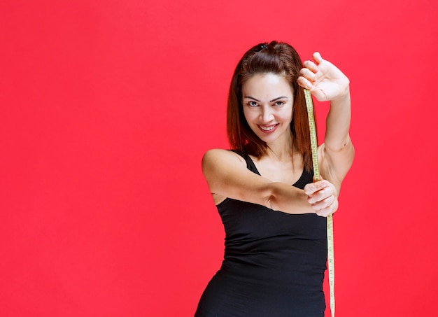 Young woman in black singlet holding a measuring tape