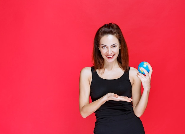 Young woman in black singlet holding a mini world globe