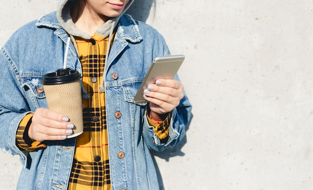 Young woman blogger browsing social media on the street. Woman texting on her phone