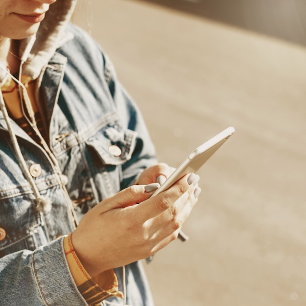 Young woman blogger browsing social networks on the street. Woman texting on her phone