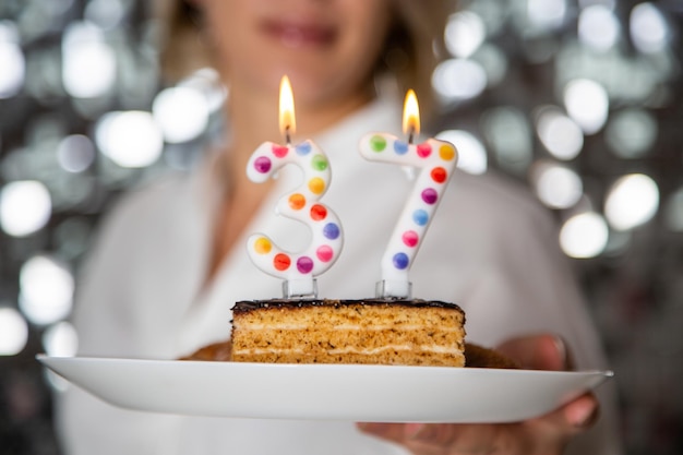 Young woman blowing candles on birthday cake, studio shot. High quality photo