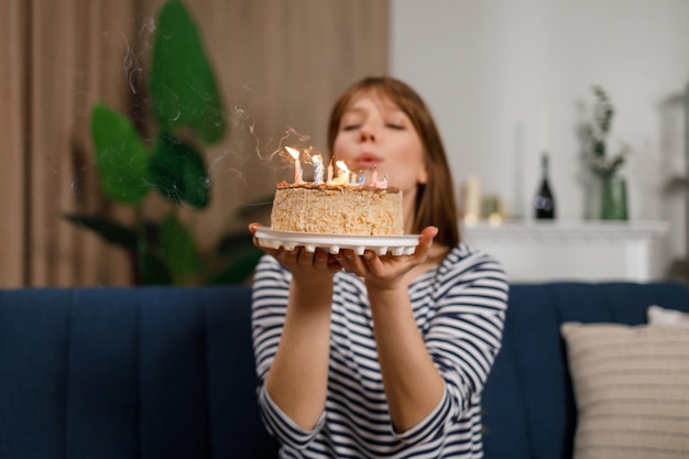 Young woman blowing out candles on birthday cake