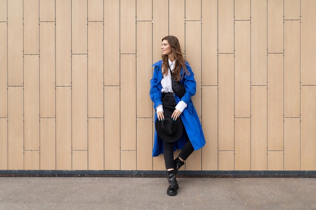 Young woman in a blue coat with a smile on the background of a city building