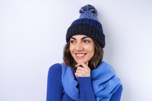 Young woman in a blue golf turtleneck hat and scarf on a white background cheery in a good mood