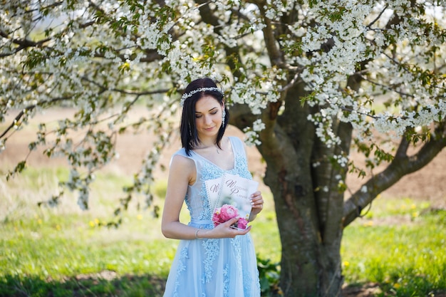 Young woman in a blue long dress holds a wedding glider in her hands