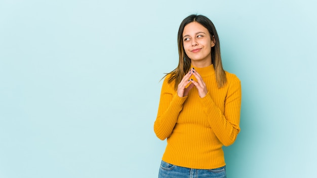 Young woman on blue wall making up plan in mind