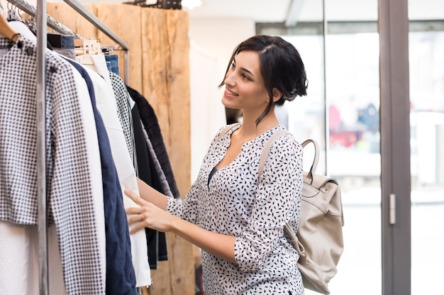 Young woman in boutique selecting new clothes to buy