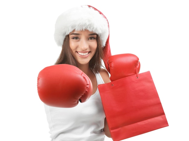 Young woman in boxing gloves with shopping bag on white background