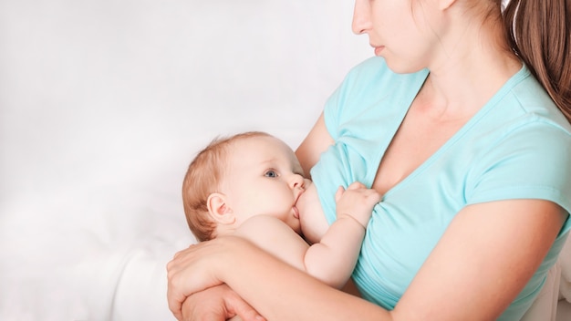 A young woman breast-feeding a baby sitting in a chair