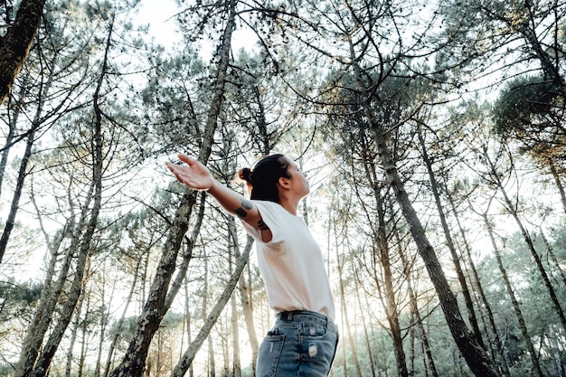 Young woman breathing clean air in nature forestFresh outdoor wellness healthy lifestyle concept concept of trees for environment global warming healthy lifestyle people in natureno pollution