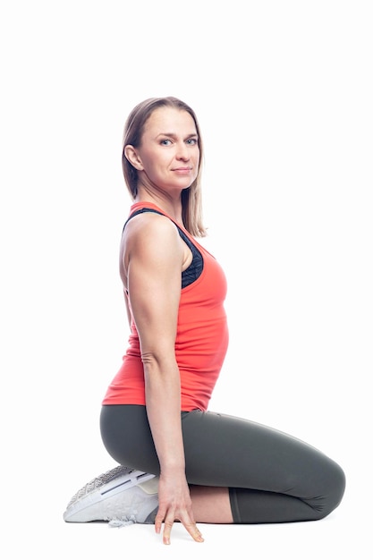 A young woman in bright sportswear sits on the floor Health and active lifestyle Isolated on white background Vertical Side view