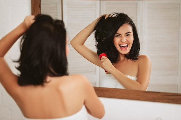 Young woman brushing healthy hair in front of a mirror