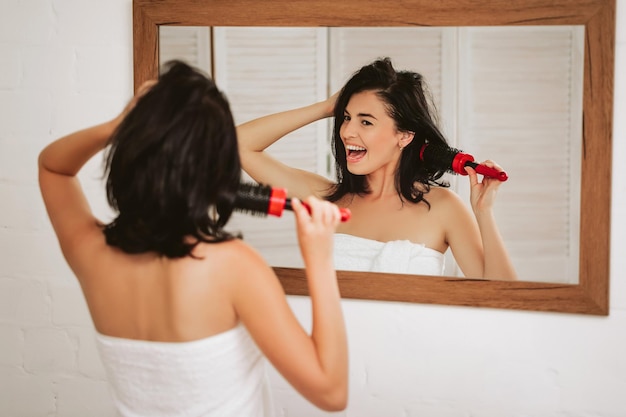 Young woman brushing healthy hair in front of a mirror