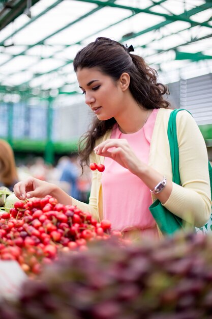 Young woman buying cherries at the market