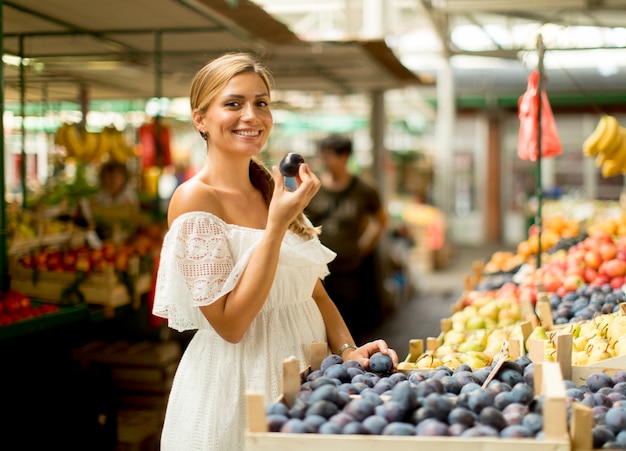 Young woman buying plums on the market