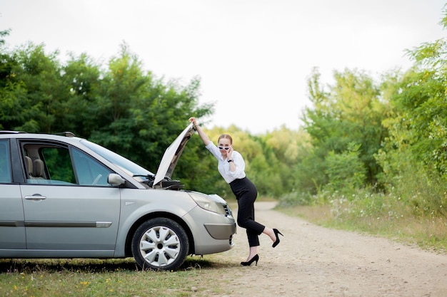 Young woman by the roadside after her car has broken down She opened the hood to see the damage