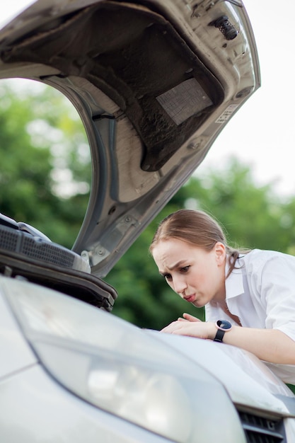 Young woman by the roadside after her car has broken down She opened the hood to see the damage