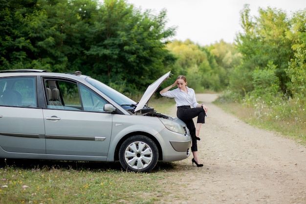 Young woman by the roadside after her car has broken down She opened the hood to see the damage.