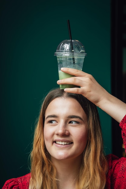 A young woman in a cafe drinks a green drink ice latte