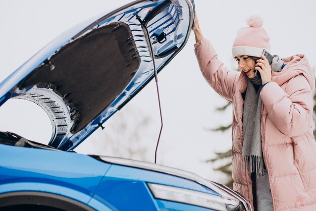 Young woman calling on the phone after her car brokedown in winter season