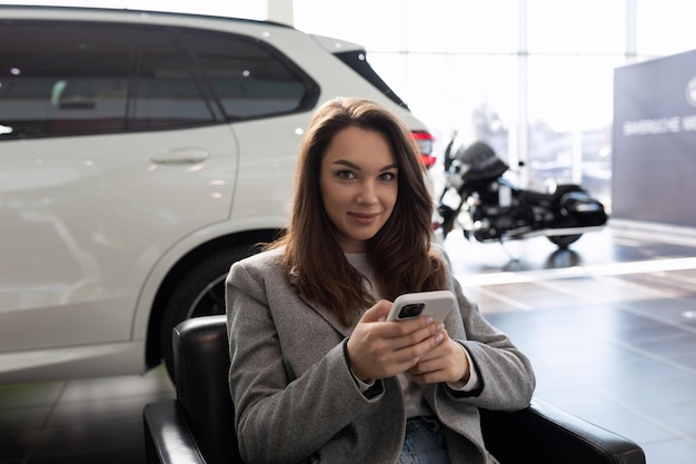 Young woman in a car dealership waiting for a sales manager of new cars