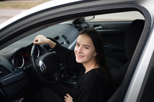 Young woman in a car got a driver's license rejoices a novice at the wheel