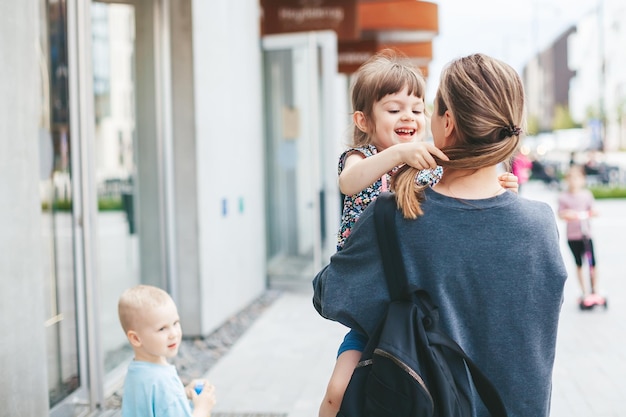 Young woman carrying her cute little daughter while walking on the street