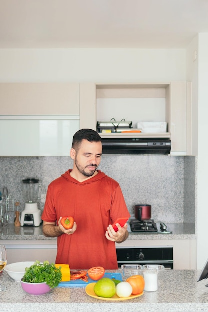 Young woman in casual clothes prepares breakfast while using cell phone for cooking